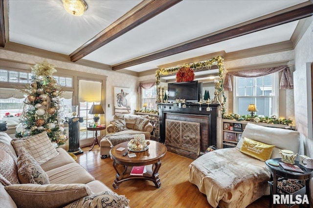 living room featuring beam ceiling, light wood-type flooring, and crown molding