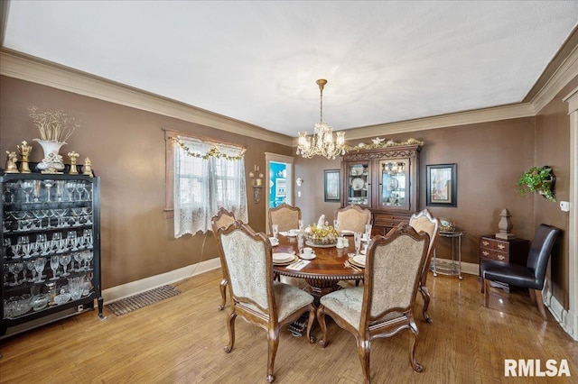 dining area featuring an inviting chandelier, light hardwood / wood-style flooring, and ornamental molding