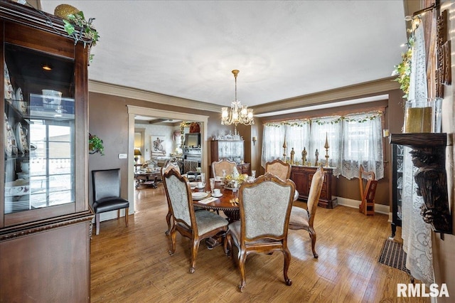 dining space with a chandelier, crown molding, and light hardwood / wood-style flooring