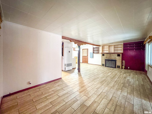 unfurnished living room with a brick fireplace, a healthy amount of sunlight, and light hardwood / wood-style flooring