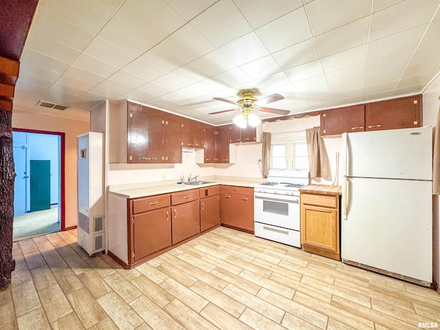 kitchen with light wood-type flooring, white appliances, and sink