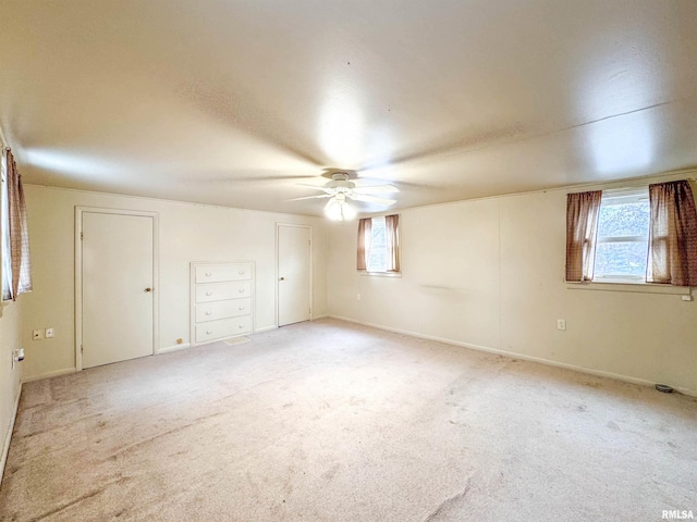 spare room with ceiling fan, a healthy amount of sunlight, and light carpet