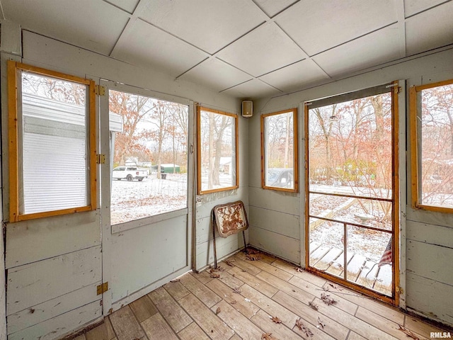 unfurnished sunroom featuring a drop ceiling and a wealth of natural light