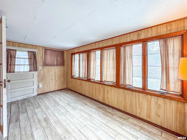 interior space featuring plenty of natural light, light hardwood / wood-style floors, and wooden walls