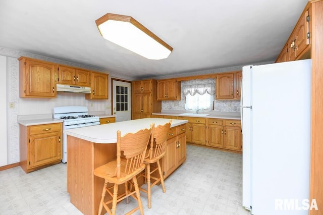 kitchen featuring white appliances, a center island, a breakfast bar area, and sink