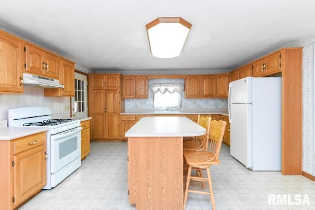 kitchen with a center island, sink, white appliances, and a breakfast bar area