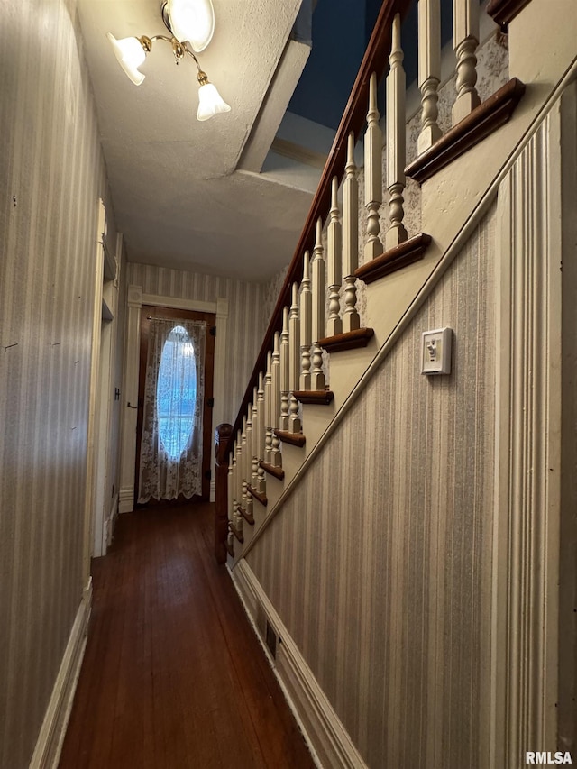 stairs with wood-type flooring and a textured ceiling