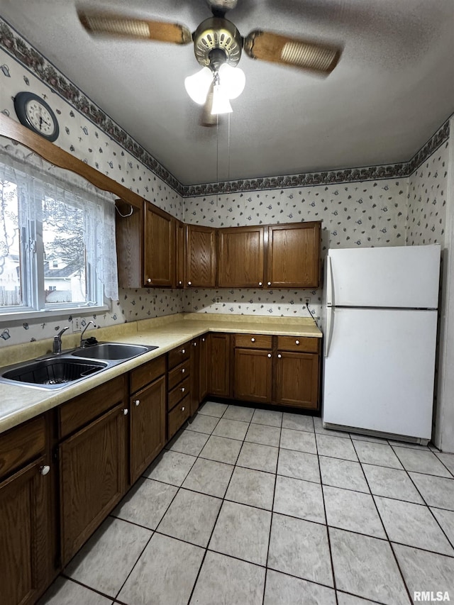 kitchen featuring ceiling fan, sink, white fridge, a textured ceiling, and light tile patterned flooring