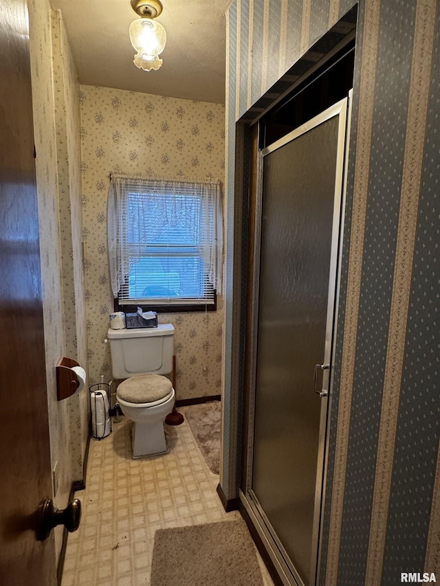 bathroom featuring toilet and a shower with shower door