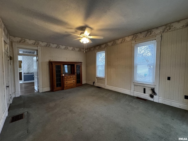 interior space with a wealth of natural light, ceiling fan, and dark colored carpet