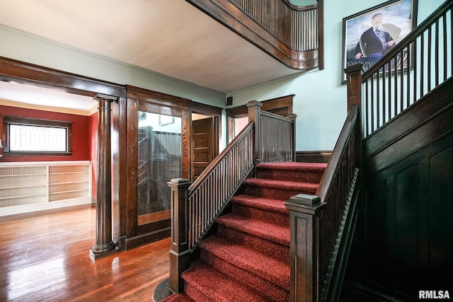 staircase with hardwood / wood-style flooring, ornate columns, and crown molding