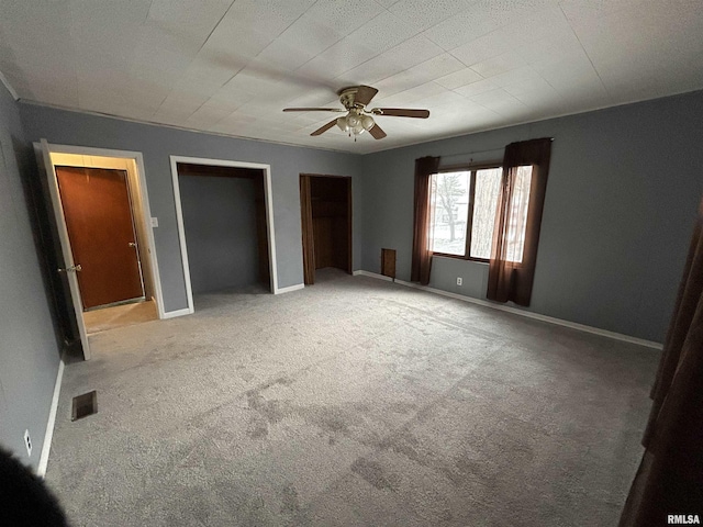 unfurnished bedroom with multiple closets, ceiling fan, and carpet floors