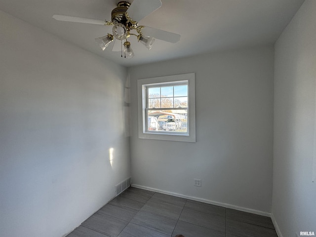 unfurnished room with ceiling fan and dark tile patterned flooring