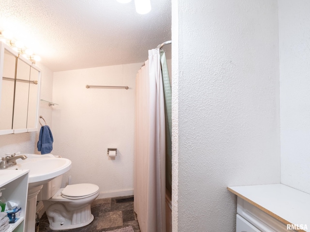 bathroom featuring walk in shower, sink, a textured ceiling, and toilet