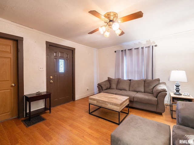 living room featuring light hardwood / wood-style flooring, ceiling fan, and crown molding