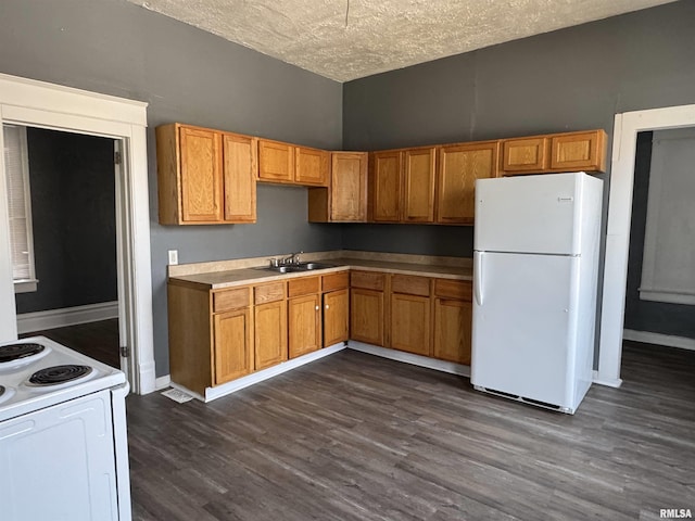 kitchen featuring a textured ceiling, sink, dark wood-type flooring, and white appliances