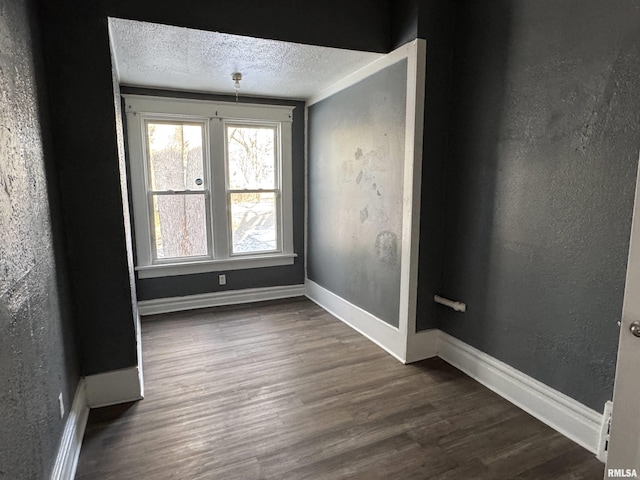 spare room featuring dark hardwood / wood-style flooring and a textured ceiling