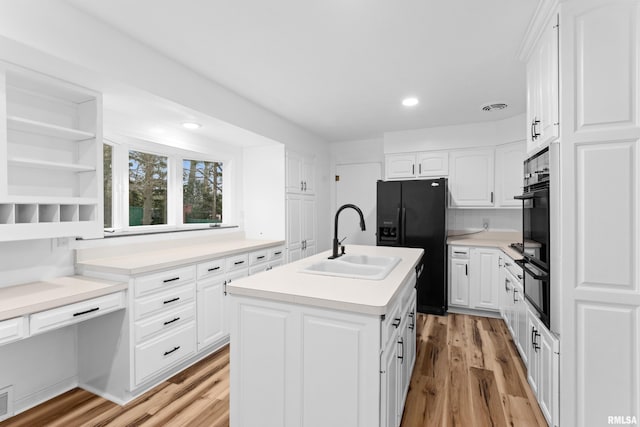 kitchen with a center island with sink, black appliances, white cabinets, and sink