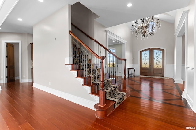 entryway with arched walkways, french doors, stairway, and wood-type flooring