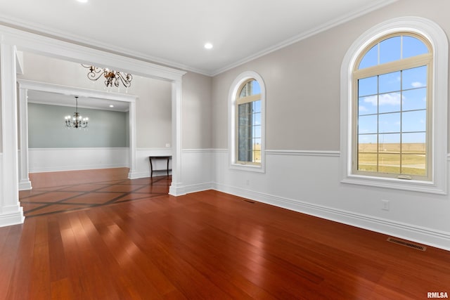 empty room featuring ornate columns, wood-type flooring, visible vents, and ornamental molding