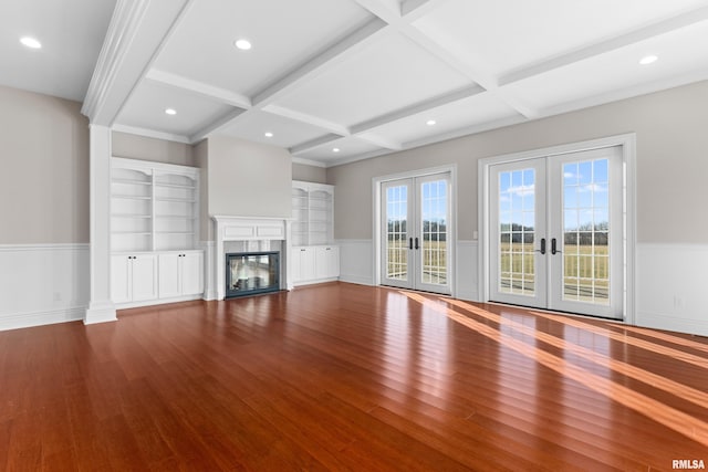 unfurnished living room featuring a wainscoted wall, a premium fireplace, wood finished floors, and french doors