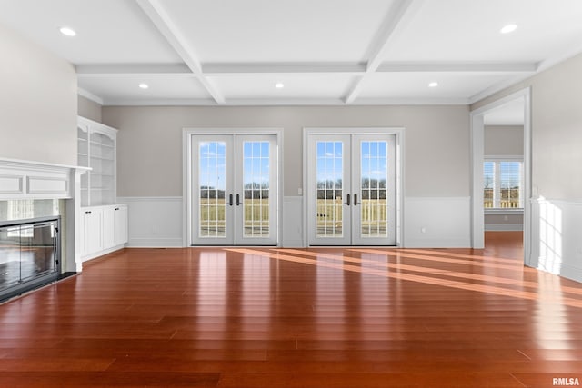 unfurnished living room featuring wainscoting, coffered ceiling, wood finished floors, and french doors