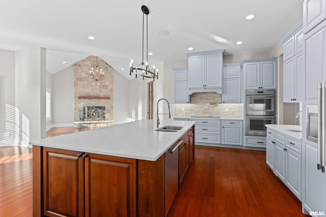 kitchen with lofted ceiling, dark wood-type flooring, a sink, light countertops, and appliances with stainless steel finishes