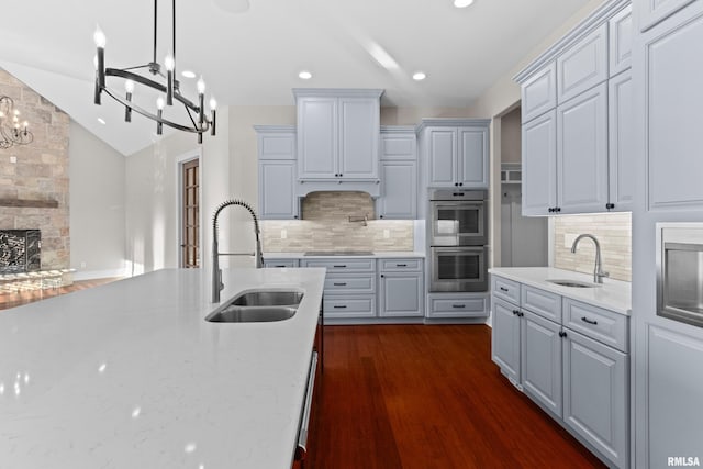 kitchen with lofted ceiling, double oven, a sink, and dark wood-style floors