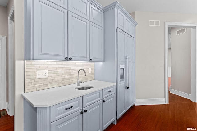 kitchen with dark wood-style flooring, visible vents, decorative backsplash, and a sink