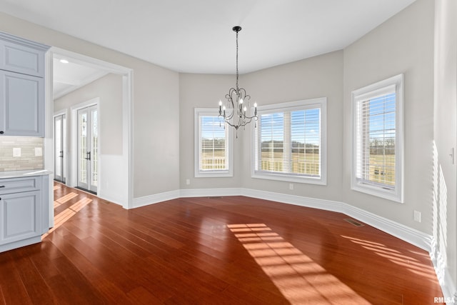 unfurnished dining area with baseboards, dark wood-type flooring, visible vents, and an inviting chandelier