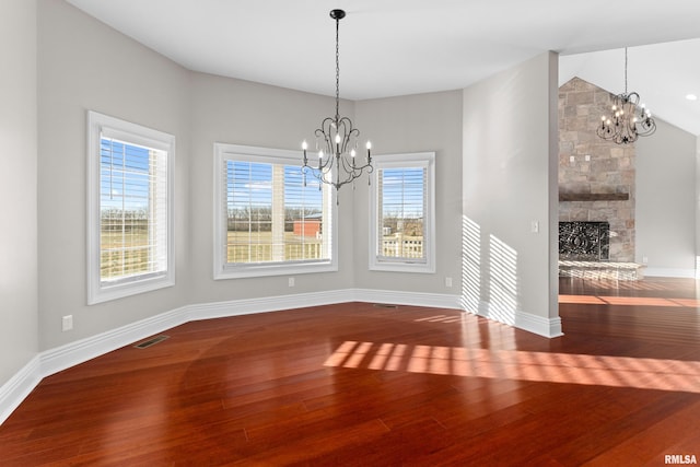 unfurnished dining area with wood finished floors, visible vents, and a notable chandelier