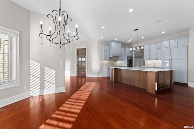 kitchen with tasteful backsplash, light countertops, a sink, and dark wood-style floors