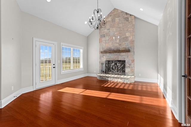 unfurnished living room with a chandelier, a stone fireplace, hardwood / wood-style flooring, and baseboards