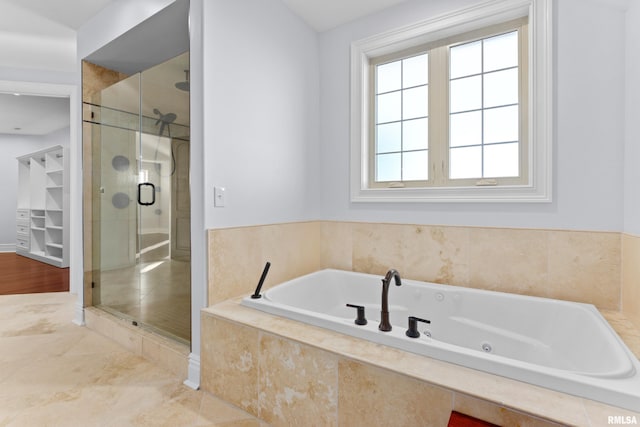 full bathroom featuring a whirlpool tub, a stall shower, and a walk in closet