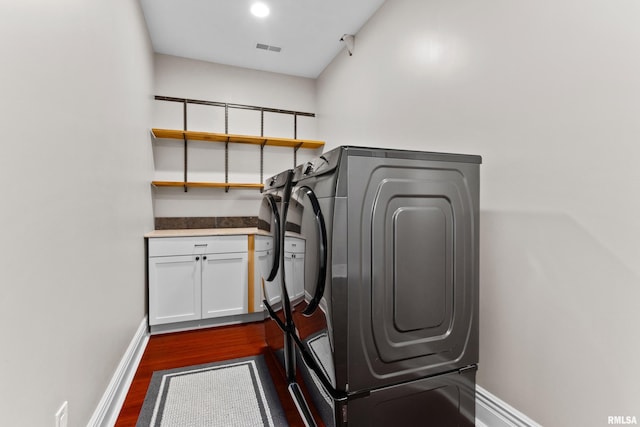 laundry room with dark wood-style floors, washing machine and dryer, visible vents, and baseboards