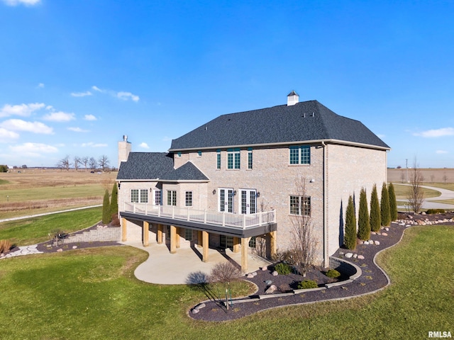 rear view of house with a patio area, a lawn, and a chimney