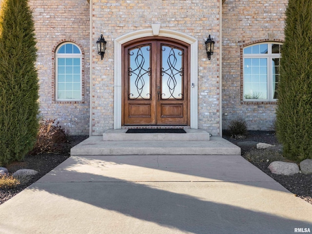 view of exterior entry featuring stone siding, french doors, and brick siding