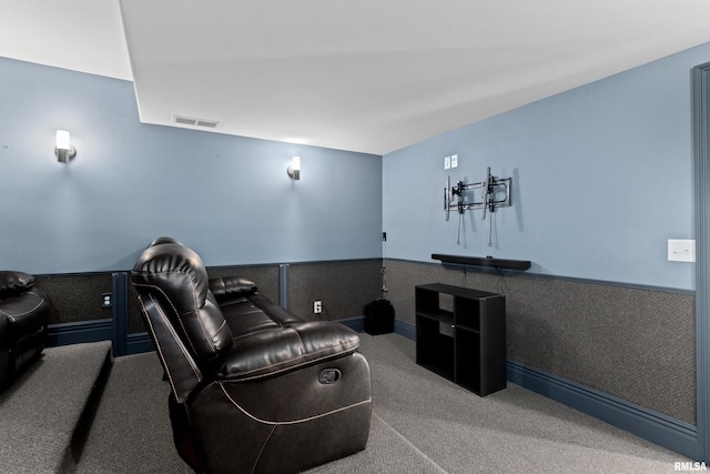 carpeted home theater room with a wainscoted wall and visible vents