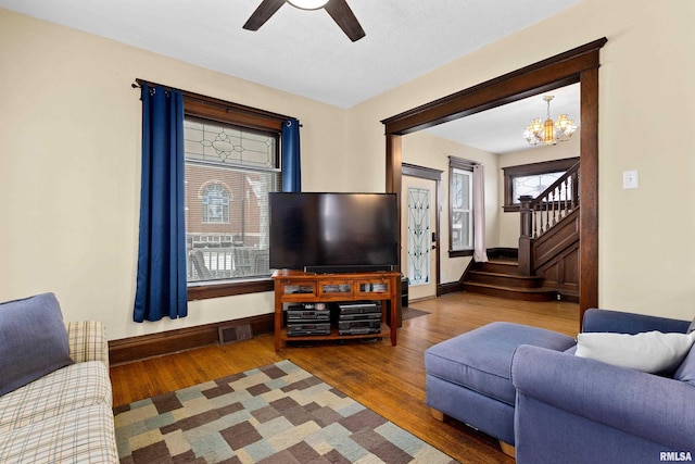 living room with ceiling fan with notable chandelier and hardwood / wood-style flooring