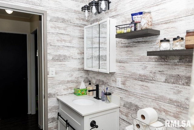 bathroom featuring wood walls, vanity, and ornamental molding