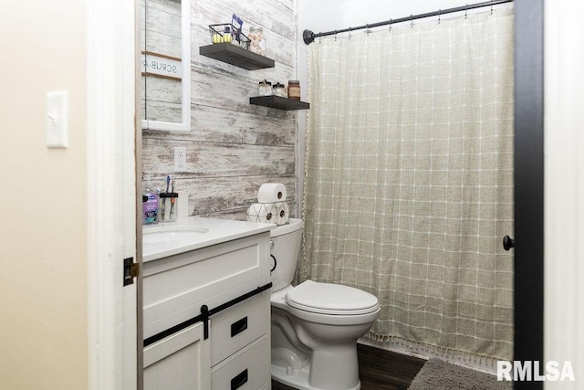 bathroom featuring vanity, wooden walls, wood-type flooring, toilet, and curtained shower