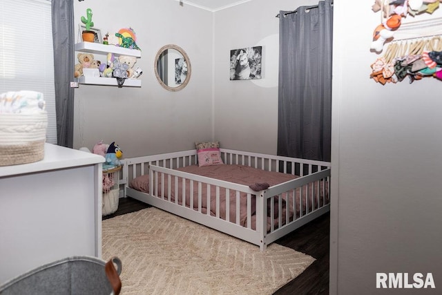 bedroom with dark wood-type flooring and a nursery area