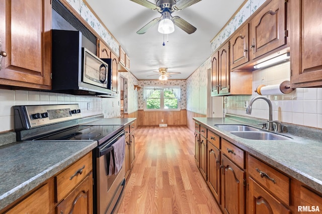 kitchen with stainless steel electric stove, sink, ceiling fan, decorative backsplash, and light hardwood / wood-style floors