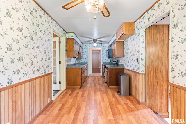 kitchen featuring stainless steel electric range, light hardwood / wood-style floors, crown molding, and sink