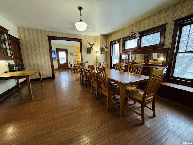 dining space with a wealth of natural light and dark wood-type flooring