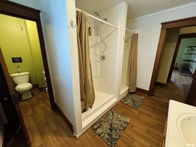 bathroom featuring a shower with curtain, toilet, wood-type flooring, and crown molding