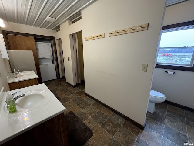 bathroom featuring vanity, stacked washing maching and dryer, and toilet