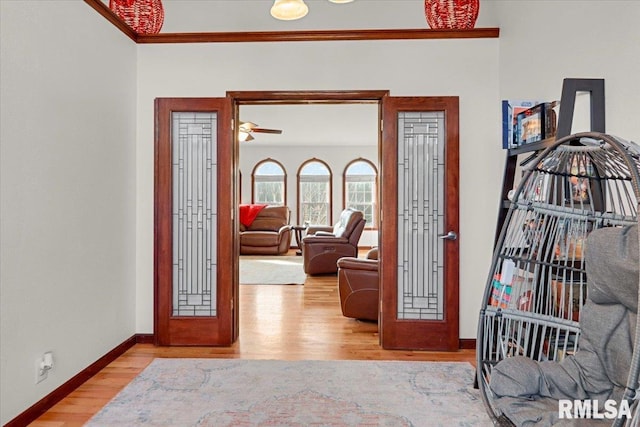 foyer entrance with french doors, light hardwood / wood-style flooring, ceiling fan, and crown molding