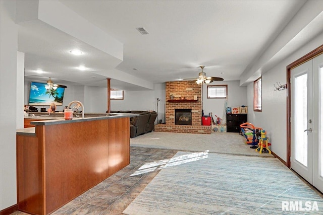 kitchen featuring a fireplace, ceiling fan, and plenty of natural light