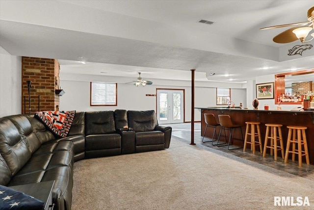 carpeted living room with bar area, french doors, and a textured ceiling